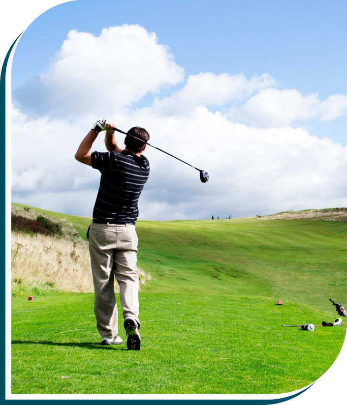 A man swinging at a golf ball on the green.